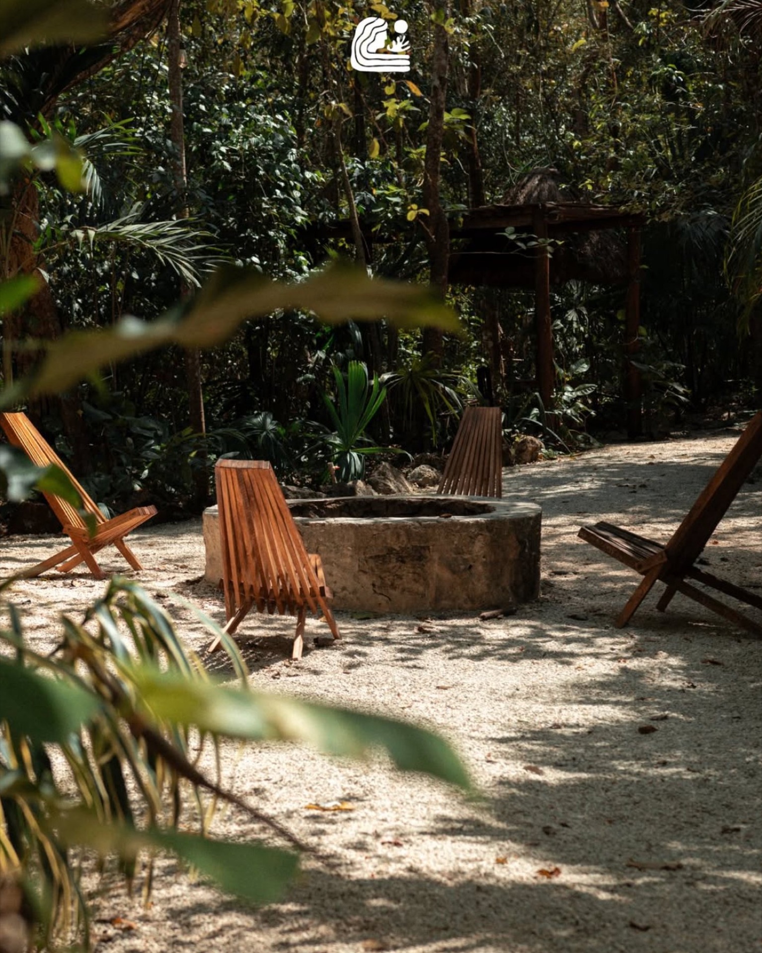 Área de fogata con sillas de madera entre la selva